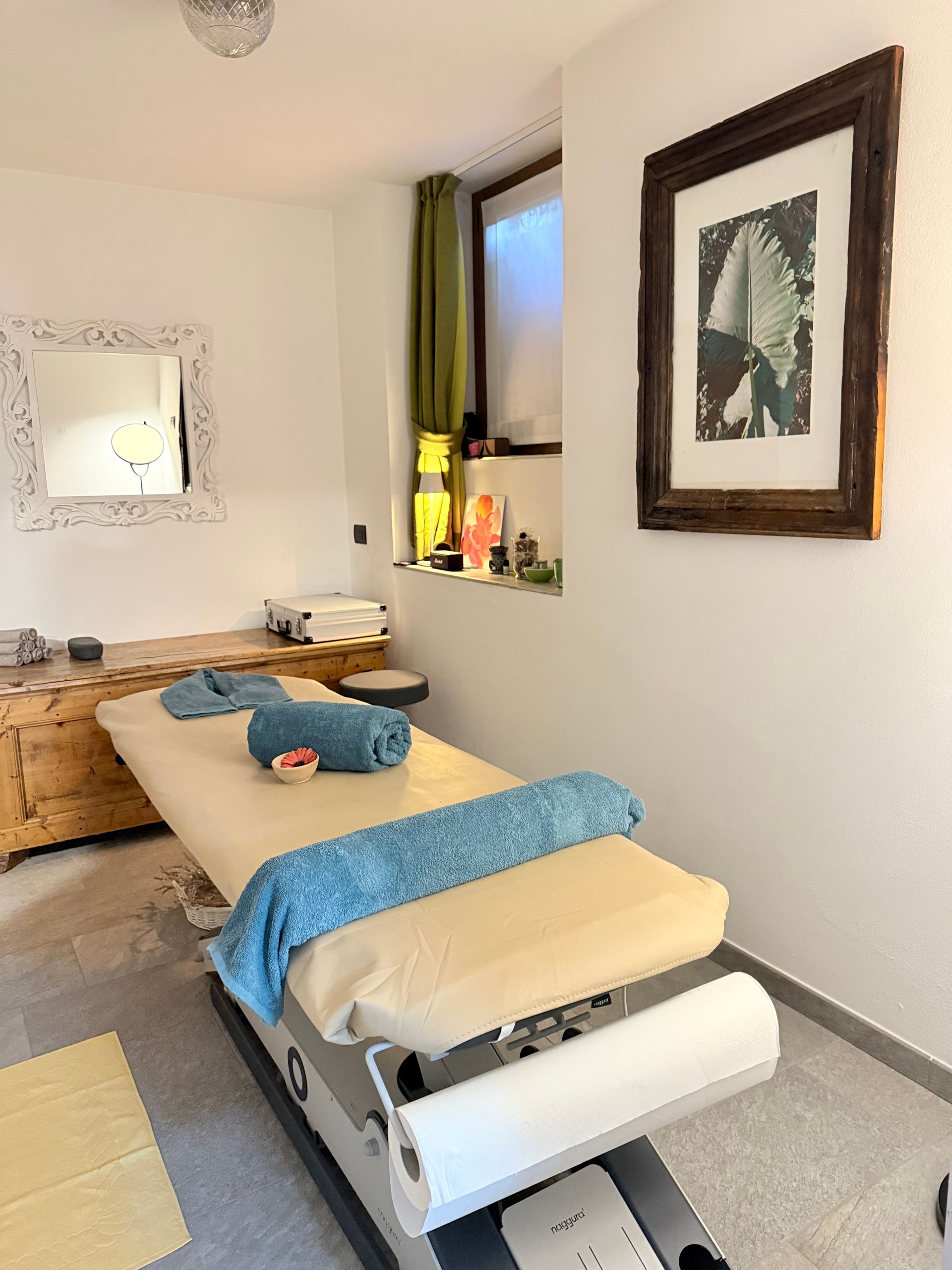 A massage table in a room with a mirror and a picture on the wall.