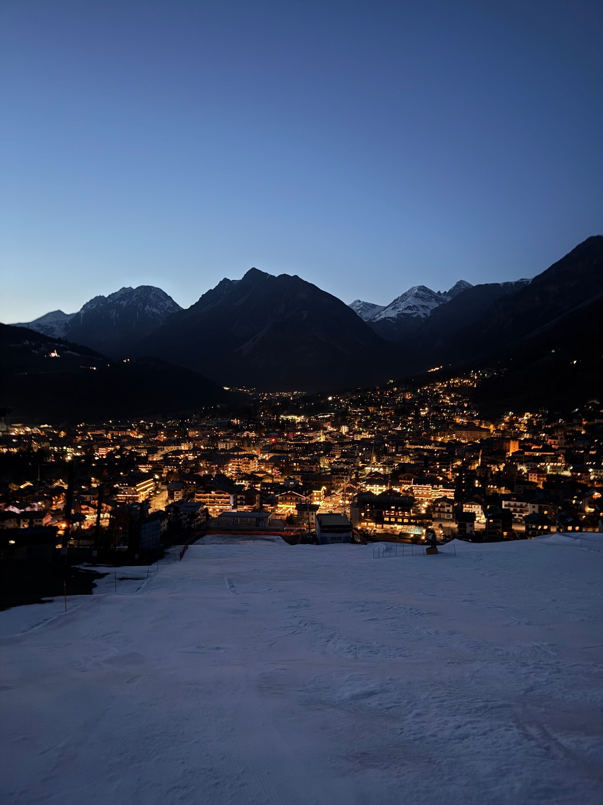 Una città è illuminata di notte con le montagne sullo sfondo