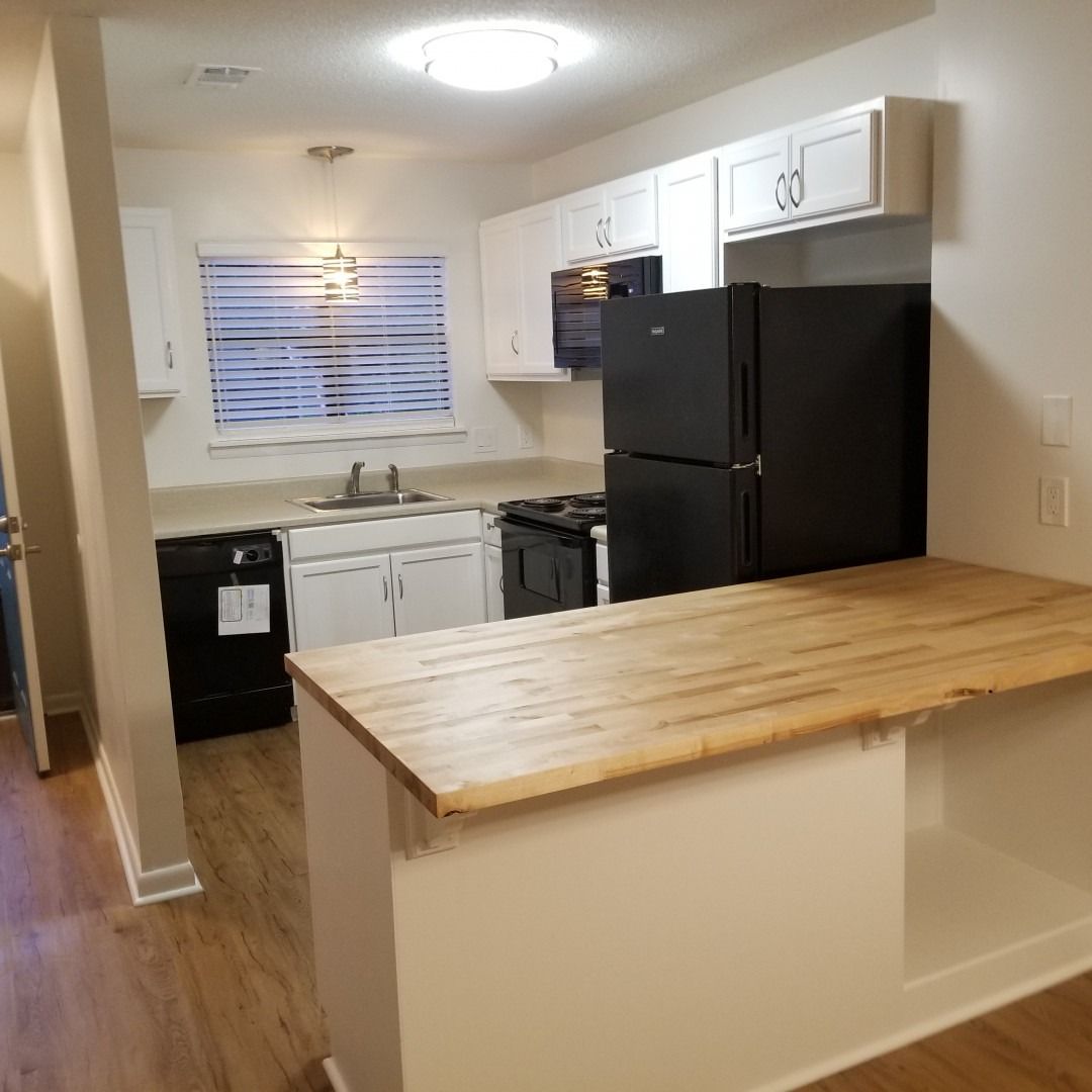 Small kitchen with white cabinets, black appliances, and a wooden island counter.