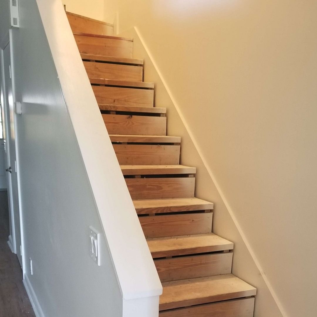Narrow indoor staircase with unfinished wooden steps and white walls