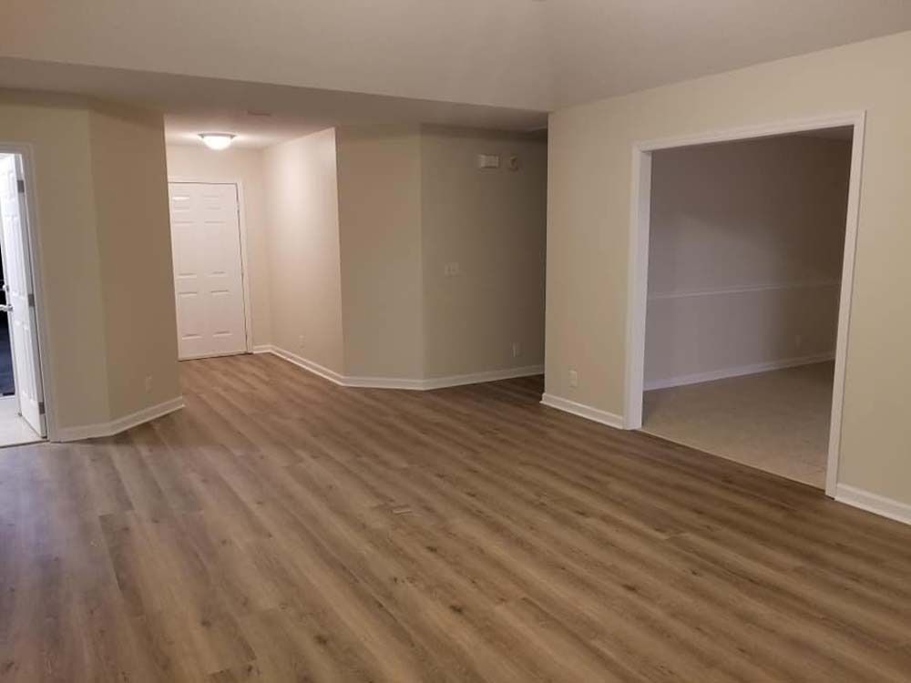 Empty beige room with wood flooring and a recessed closet opening