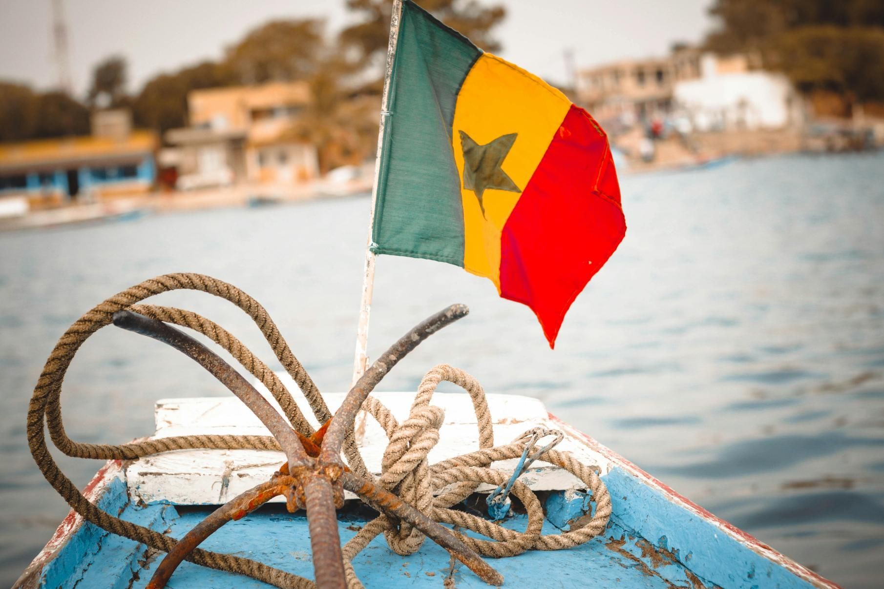Senegalese flag waving on a boat at sea; rope and anchor in focus.