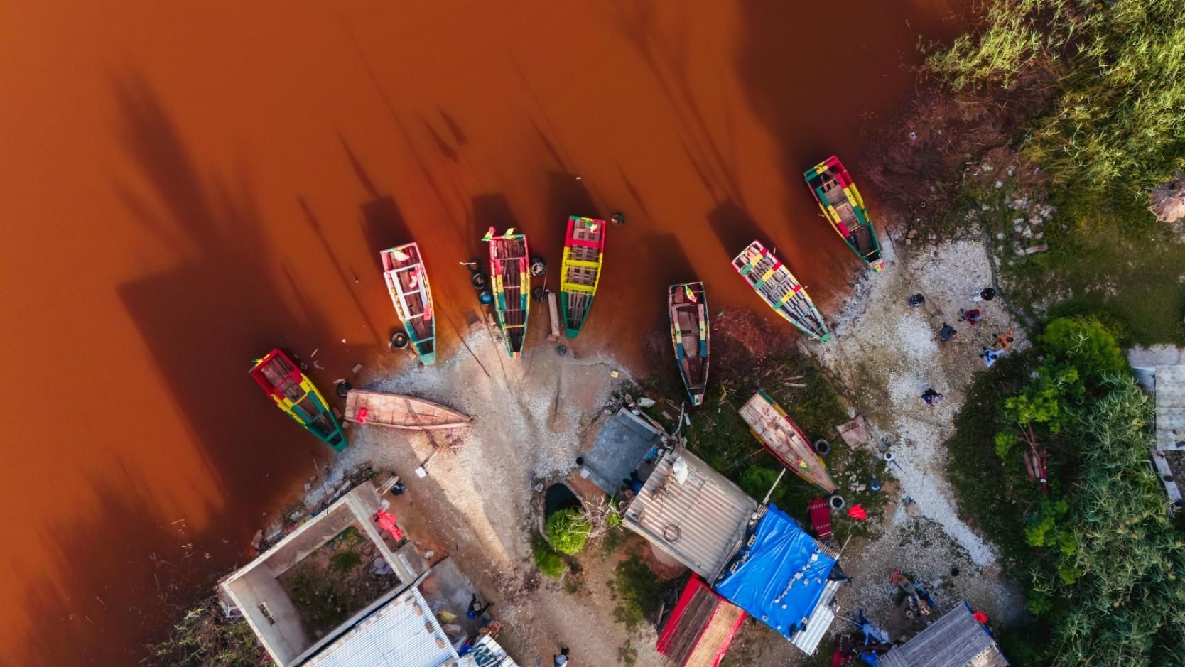 Boats docked along a muddy, red shoreline. 