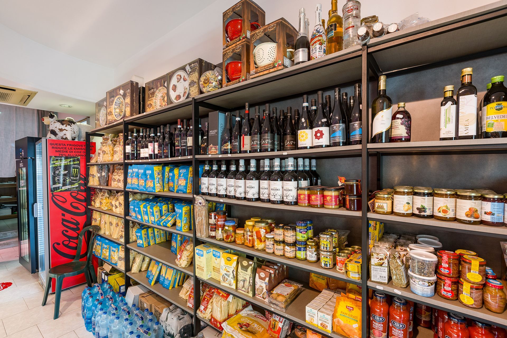 In una luminosa stanza simile a una cucina, scaffali colorati in dispensa pieni di barattoli, snack e bottiglie.