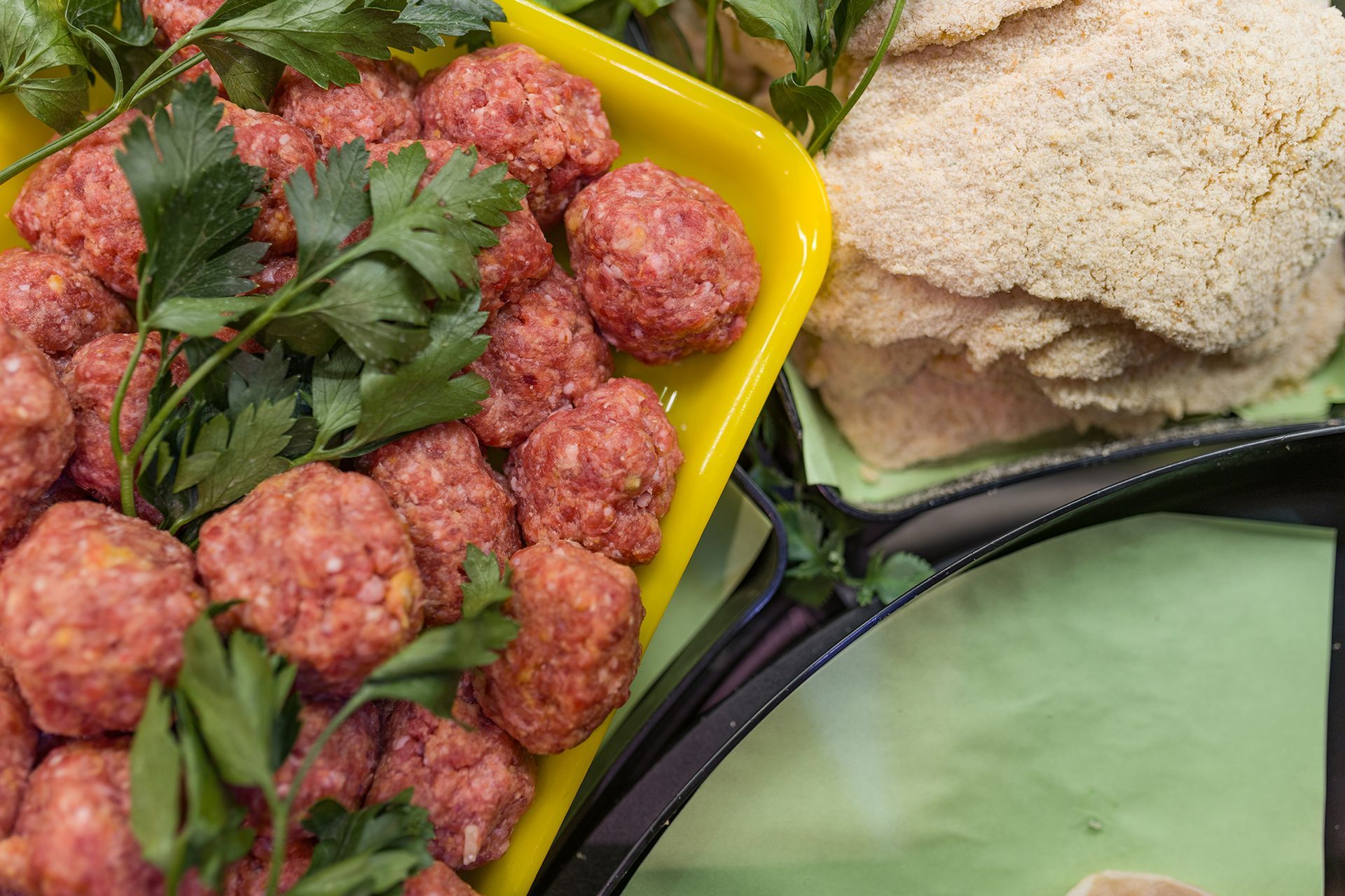 Piatto di polpette crude alle erbe aromatiche, accompagnato da pane pita e un vassoio di verdure.