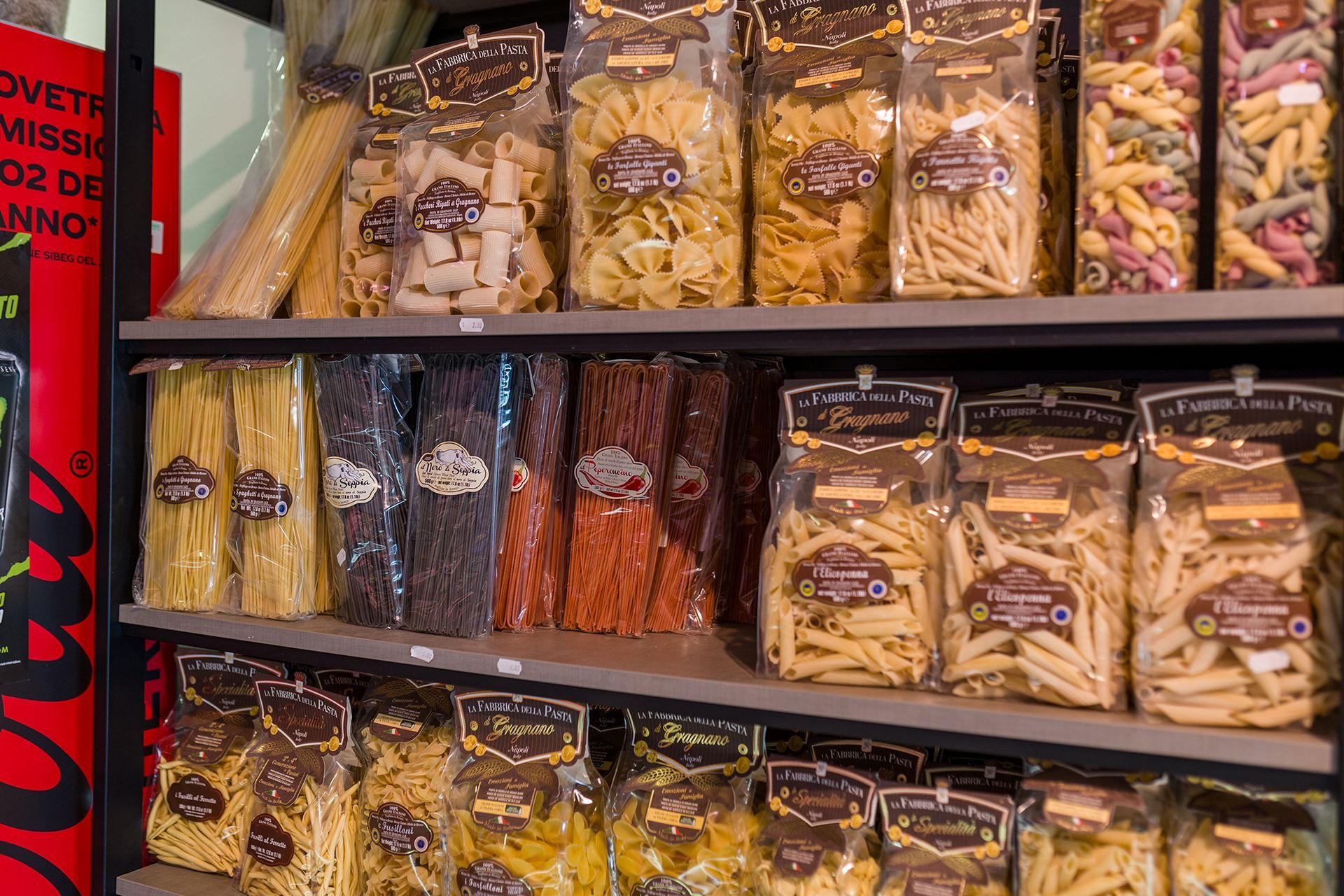 Scaffali di snack confezionati in una corsia del supermercato, con un assortimento di prodotti secchi e cracker in sacchetti trasparenti.