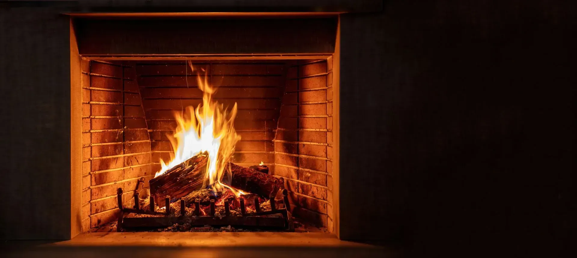 Glowing fire burning in a brick fireplace, casting warm orange light