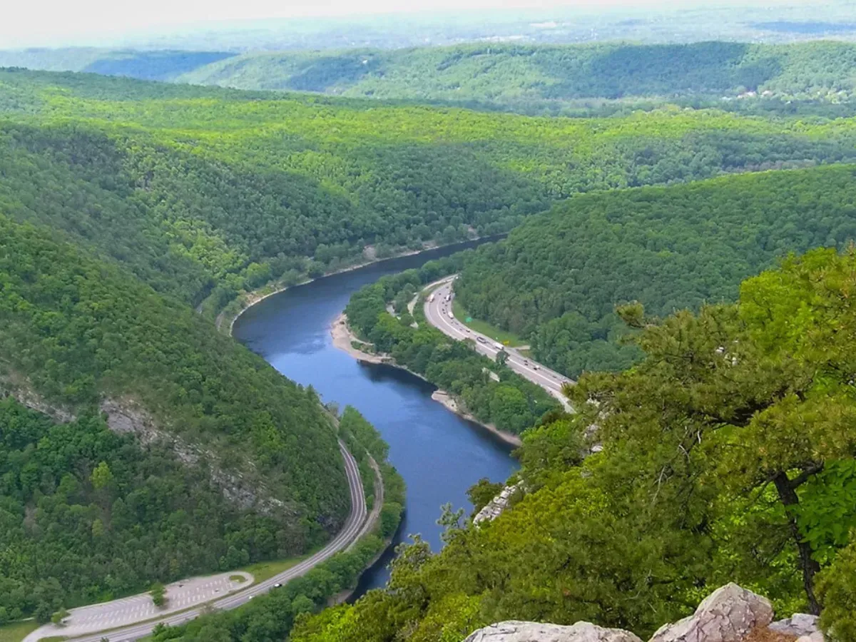 Winding river through lush green hills with a road along the shoreline