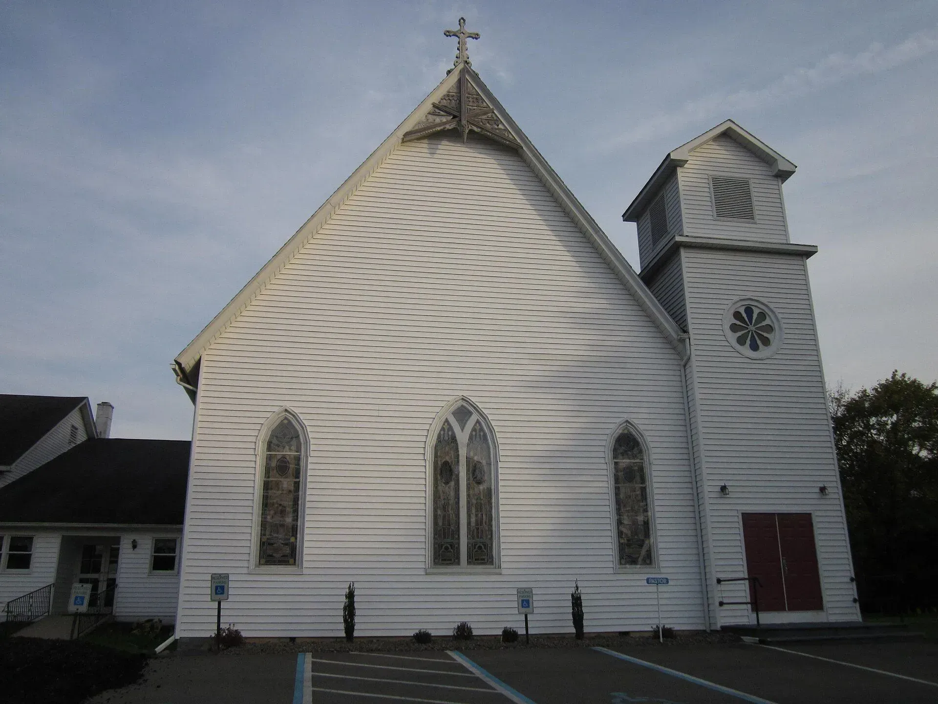 White church with steeple and red doors under a cloudy sky