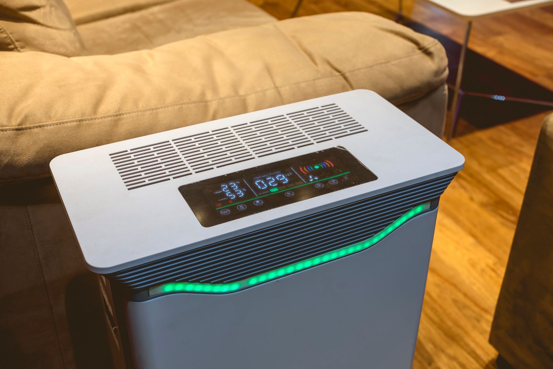 A white air purifier is sitting in a living room next to a couch.