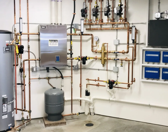 A room with a lot of pipes and a heater on the wall.