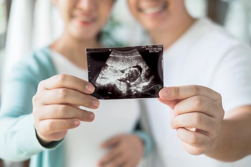 Een man en een zwangere vrouw houden een echo van hun baby vast.