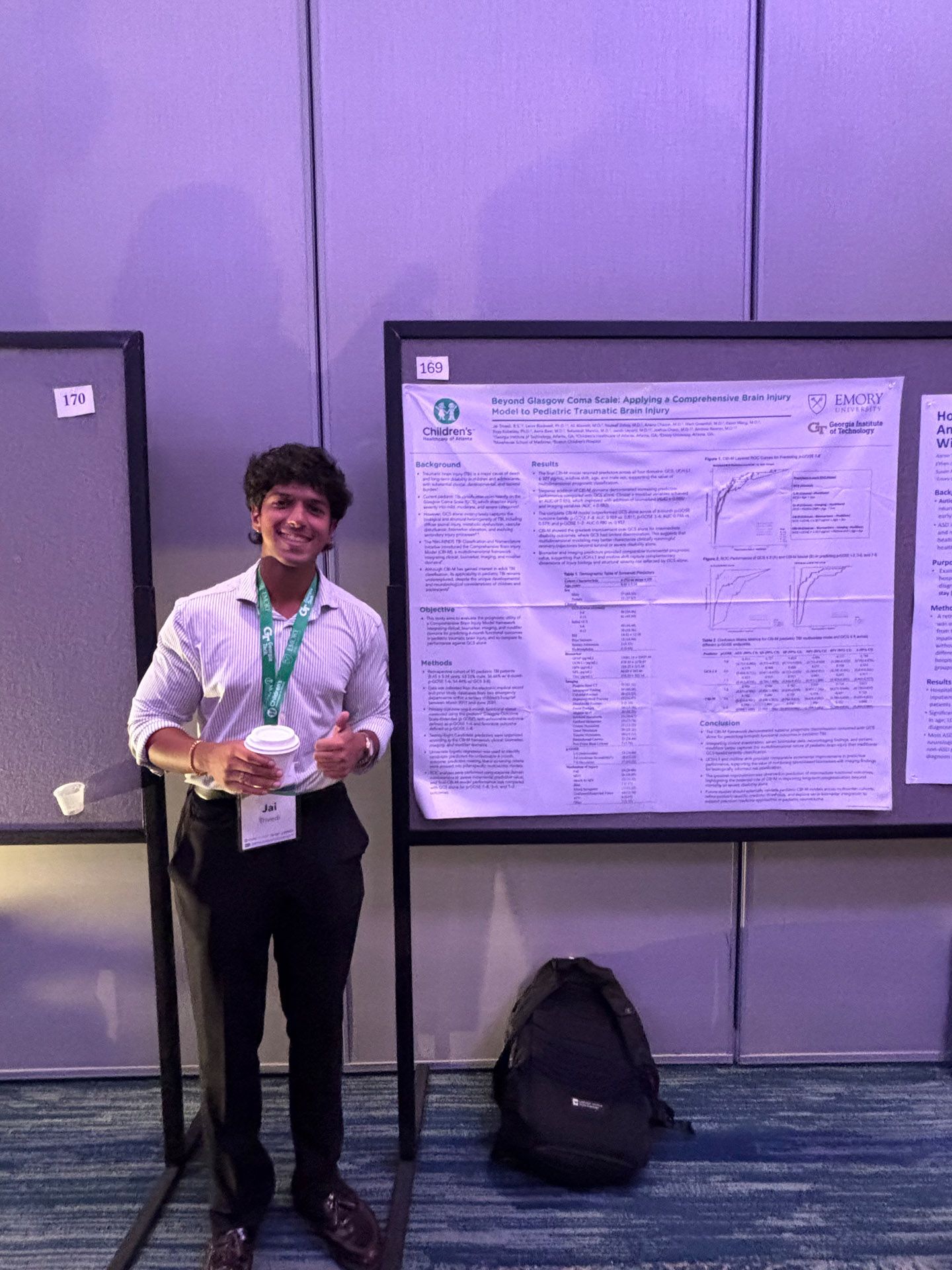 Person holding a trophy at a conference poster presentation, standing beside a large research poster.