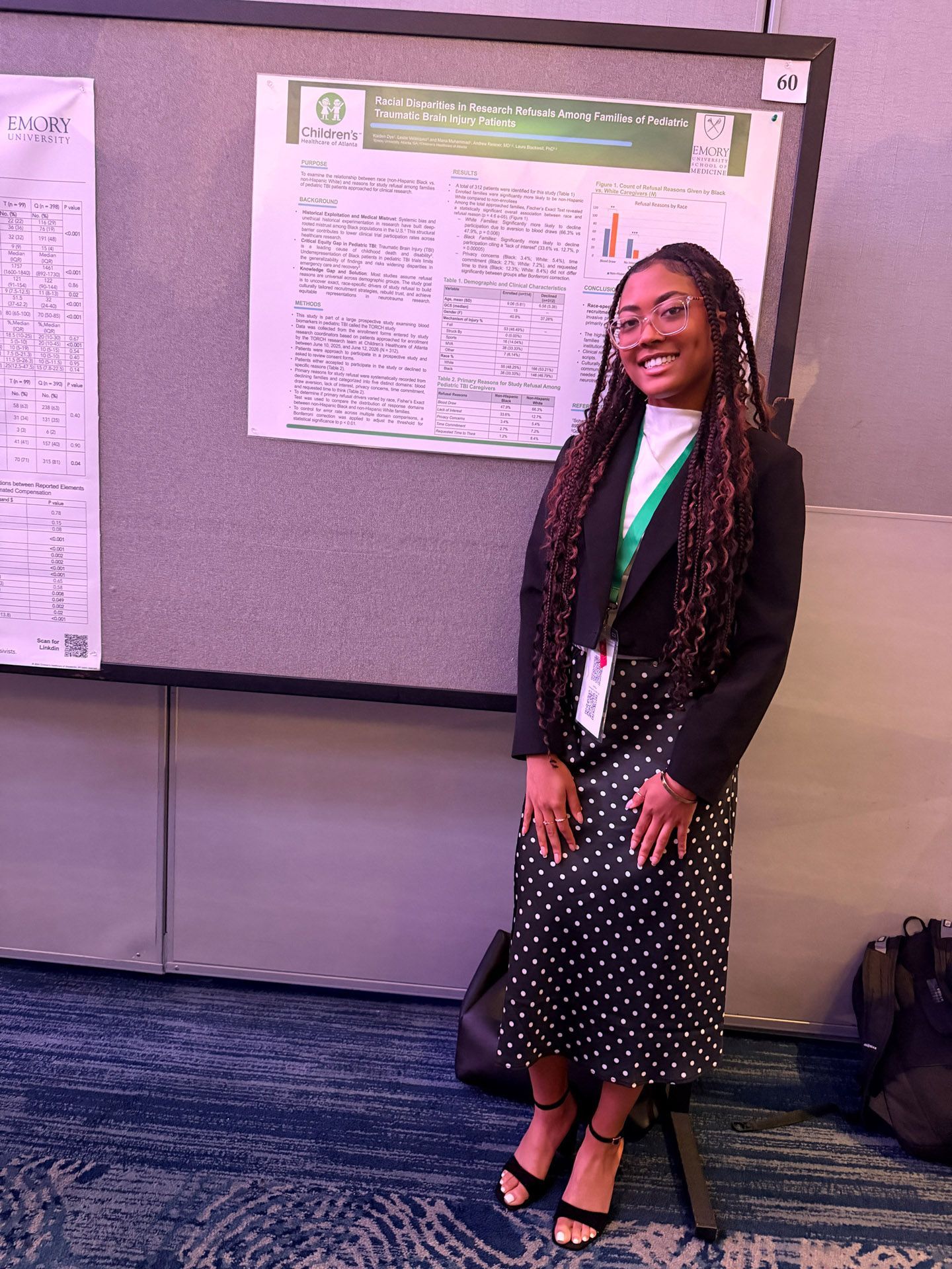 Woman standing and smiling beside a poster presentation in a conference room