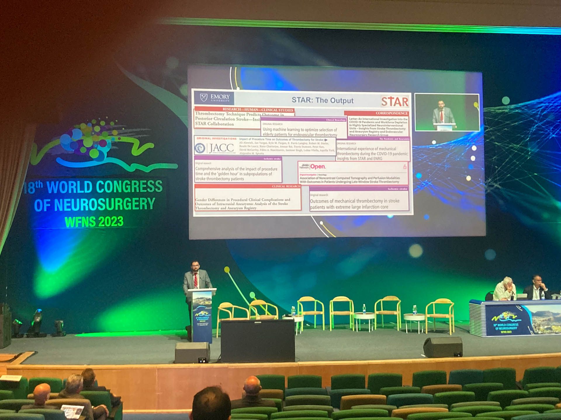 Dr. Alawieh pictured presenting on Dissecting the Role of Complement in Triggering Acute TBI and Its Progression to Chronic Encephalopathy A slide is projected with text and graphics.