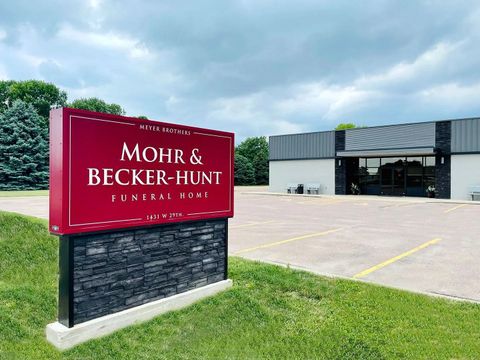 Mohr & Becker-Hunt Funeral Home sign beside a parking lot and building under cloudy skies