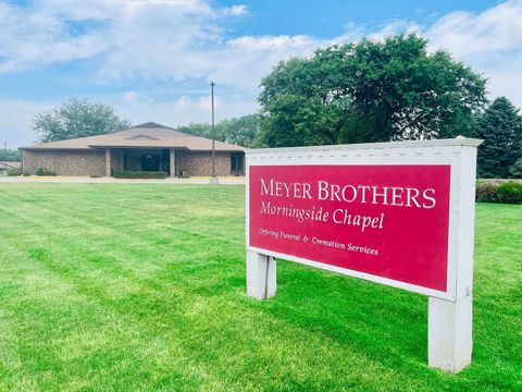 Meyer Brothers Evergreen Chapel sign on a grassy lawn with a brick building and trees behind it