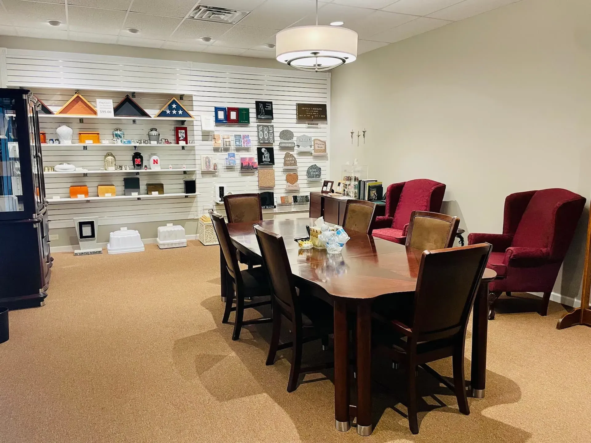 Conference room with wooden table, red chairs, shelves, and display wall in the back.