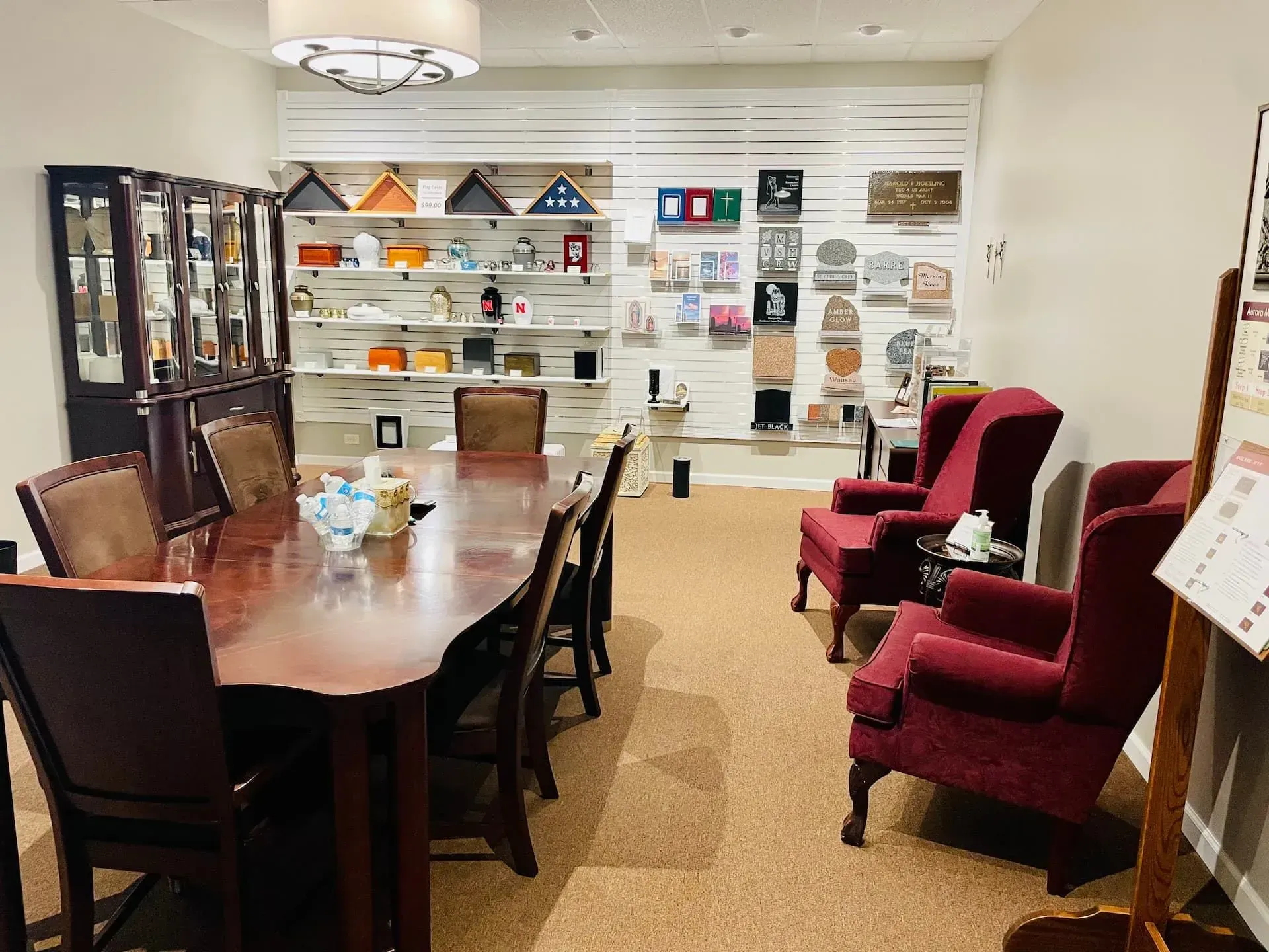 Conference room with long wooden table, chairs, red armchairs, and wall displays of samples and brochures.