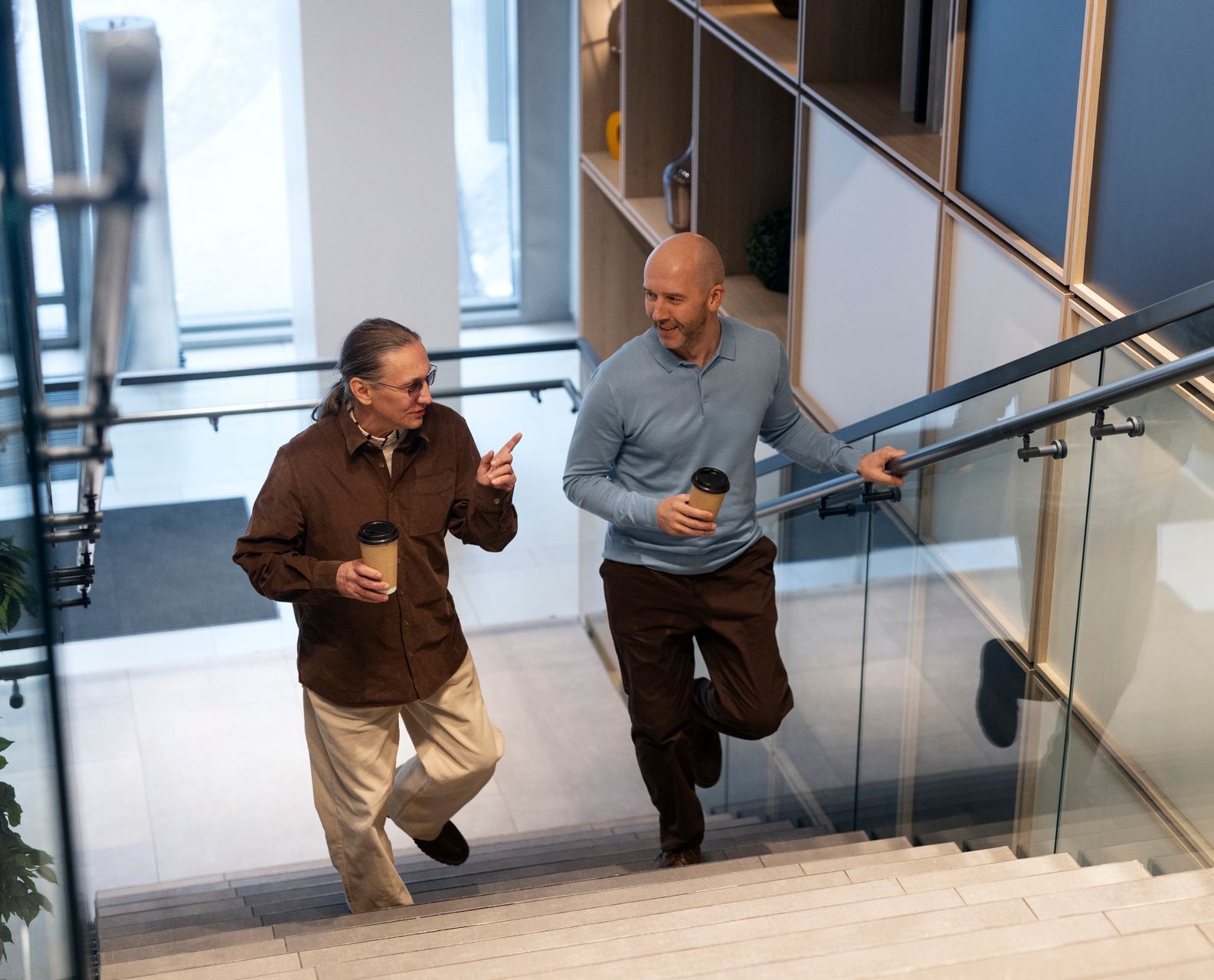 Two men are walking down stairs and talking to each other