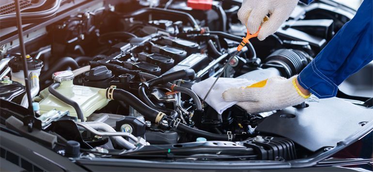 Mechanic in white gloves checking a car engine with a tool in an auto repair shop