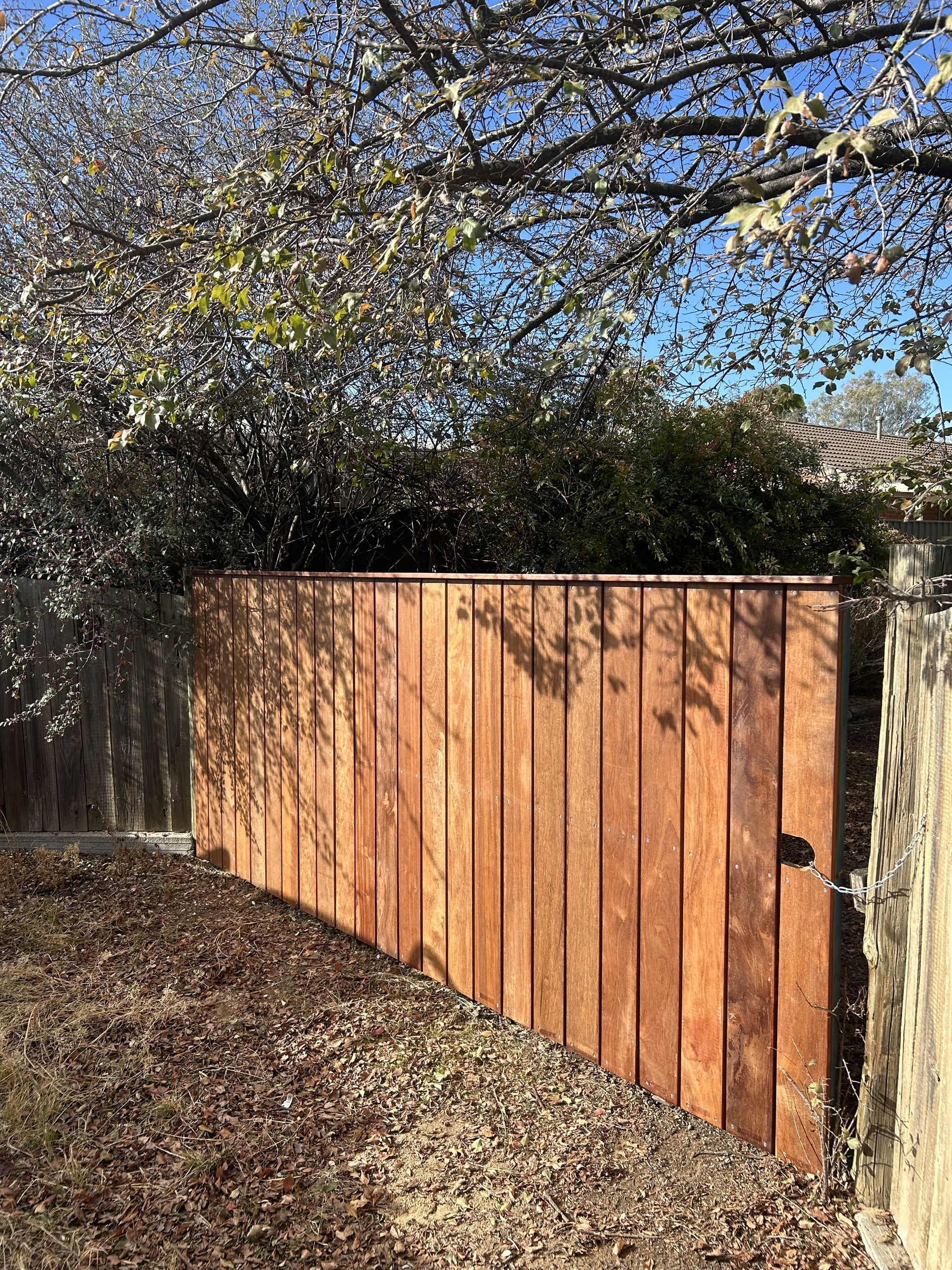Wooden gate in a yard, with shadows and foliage in the background under a blue sky — The Wright Way Building In North Albury, NSW