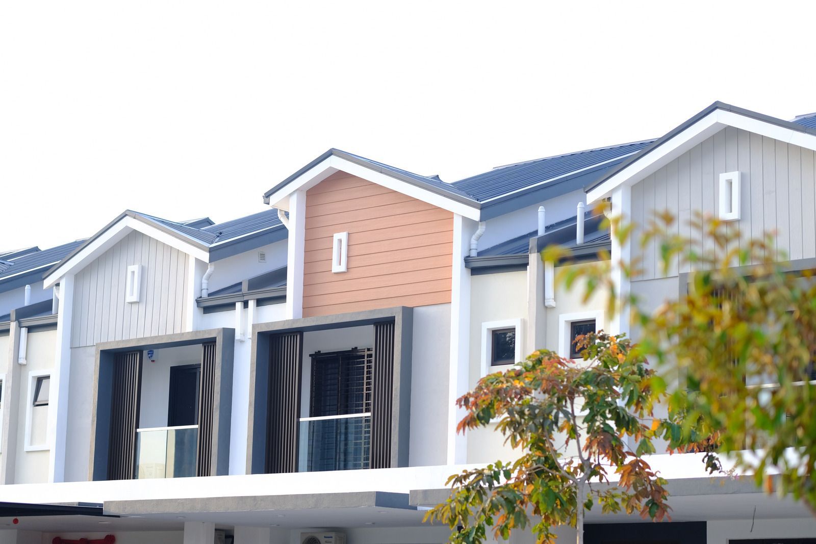 Row of modern townhouse facades with blue roofs and a brick accent wall