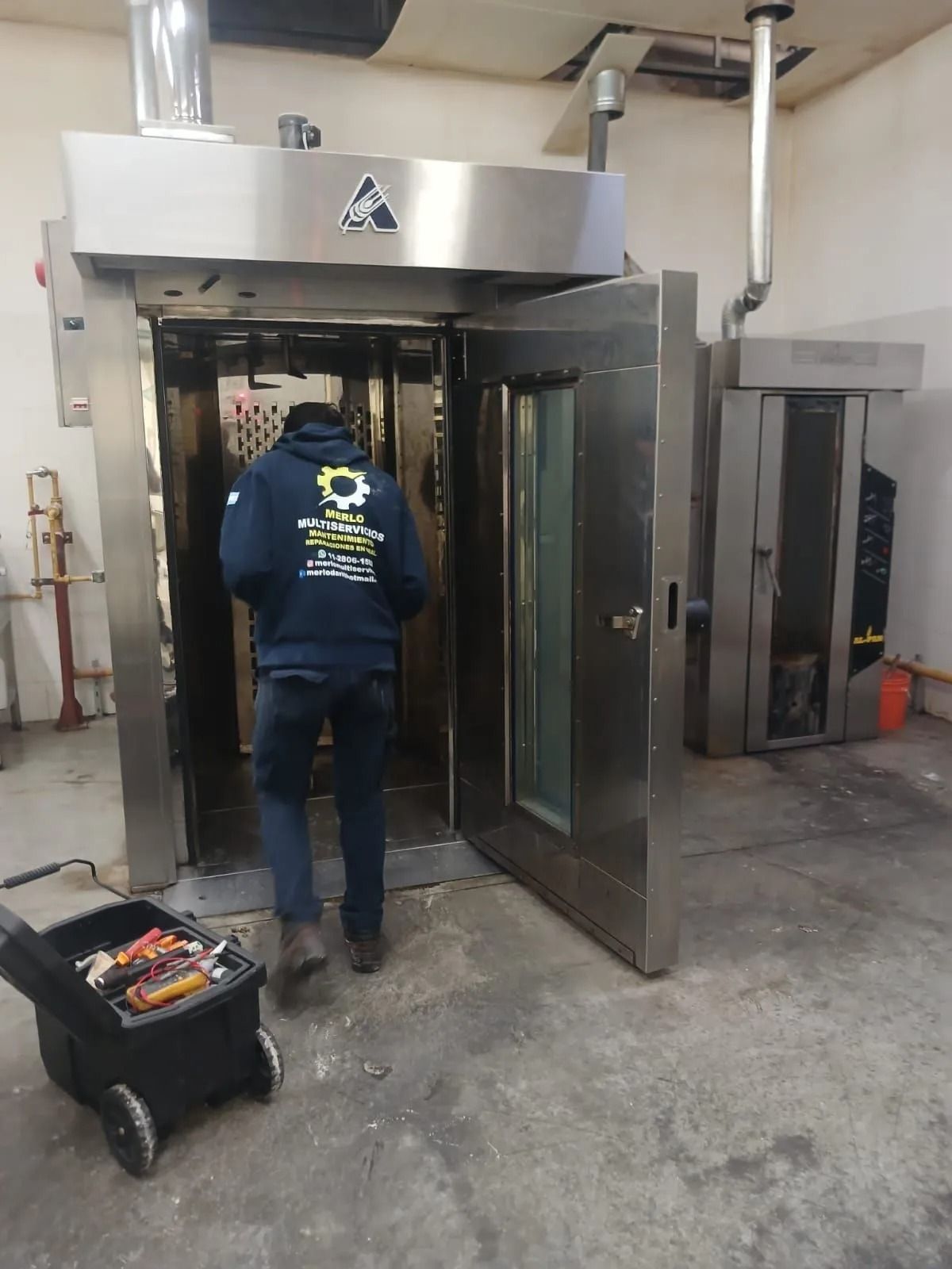 Un trabajador carga un carro en una gran máquina industrial en una sala que parece un almacén.