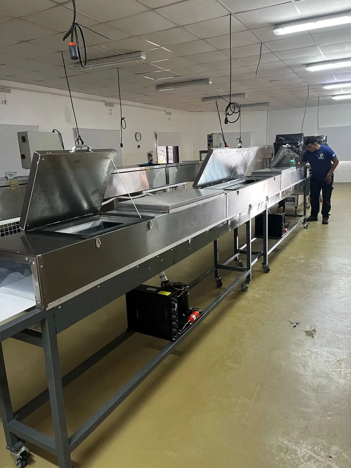 Puesto de trabajo industrial con equipos de acero inoxidable y un trabajador en una fábrica.