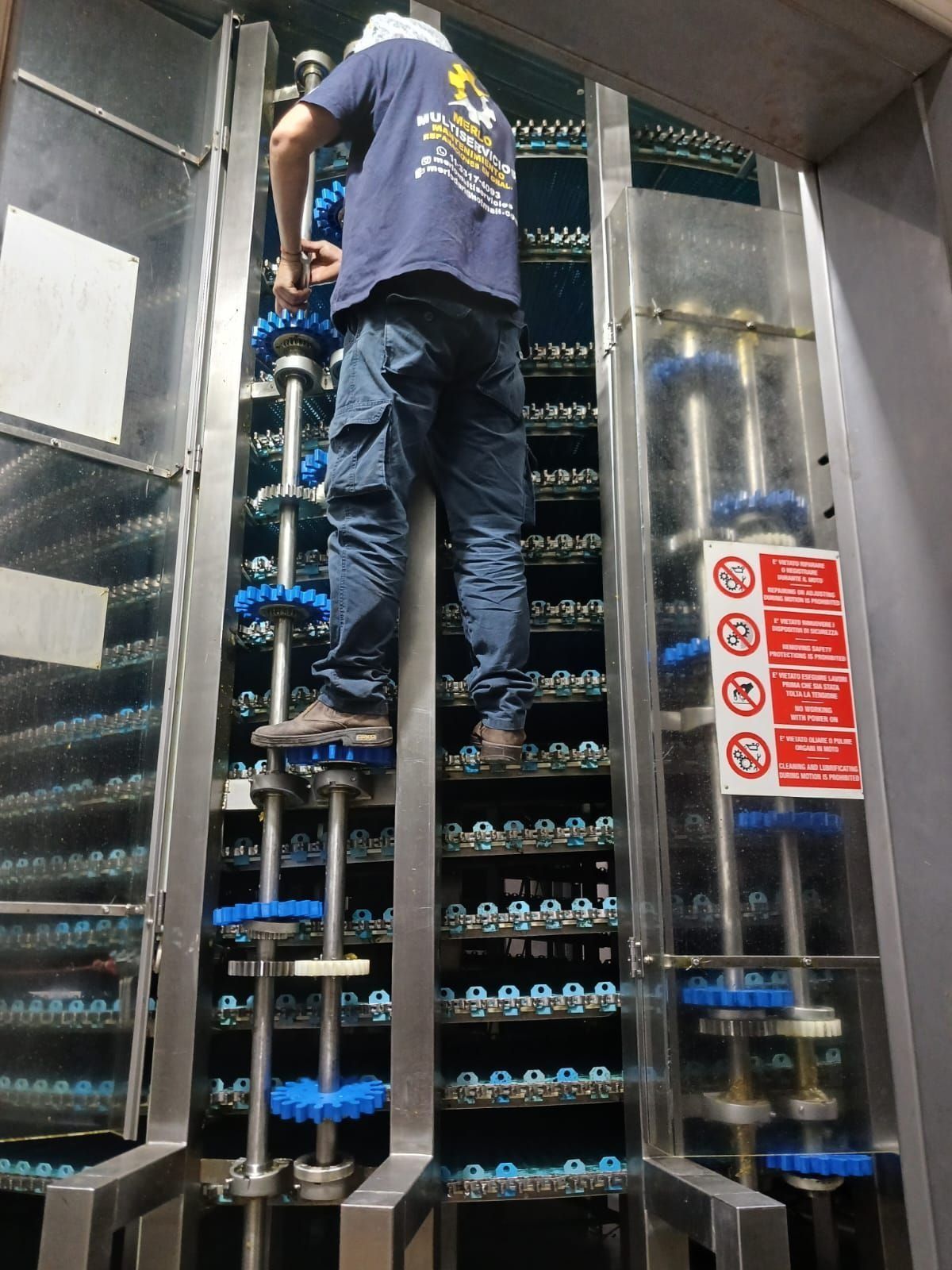 Un trabajador se encuentra subido a unas escaleras de estantería dentro de un almacén