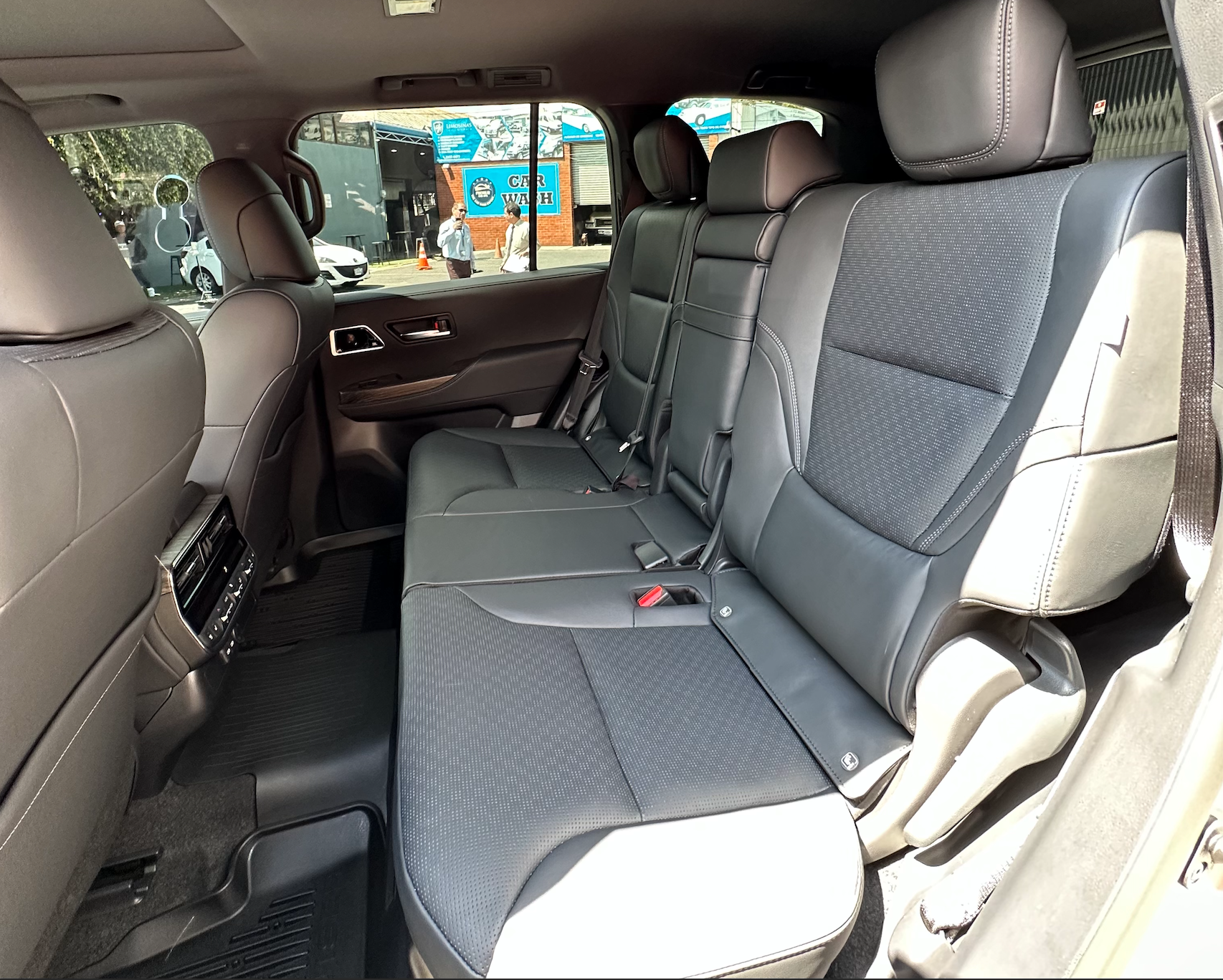 Asiento trasero de coche gris con reposabrazos plegado, visto desde la puerta trasera abierta.