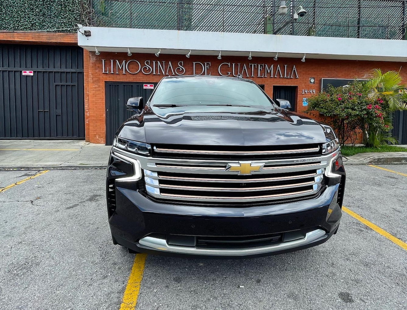 Un SUV Chevrolet negro estacionado frente a un edificio con puerta de garaje y letrero.