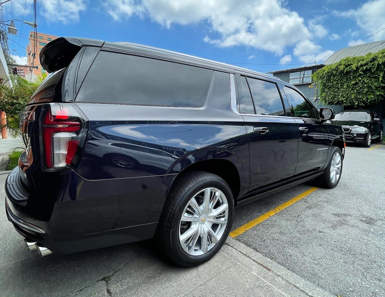 SUV azul oscuro estacionado en una calle junto a un edificio, vista trasera lateral bajo cielos nublados.