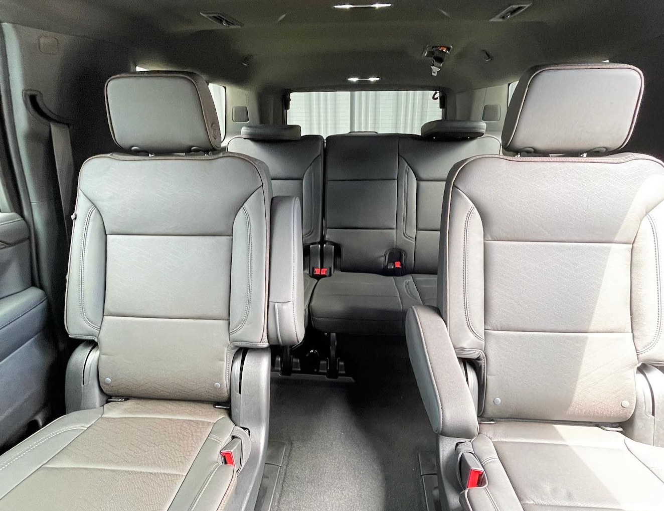 Interior de monovolumen de cuero gris con dos asientos delanteros tipo capitán y un asiento corrido en la tercera fila.