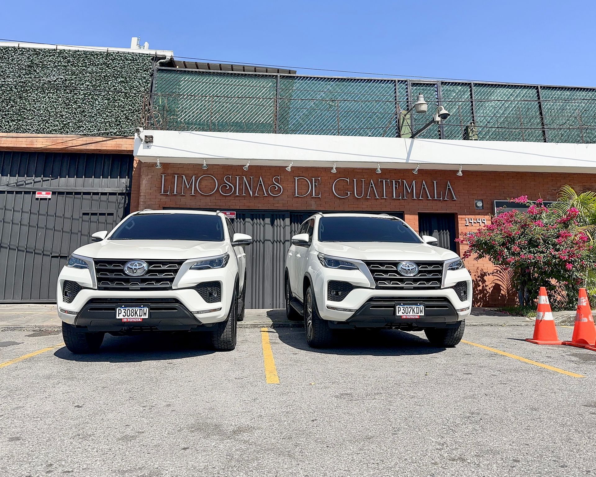 Dos camionetas blancas estacionadas una al lado de la otra frente a la entrada de un restaurante.