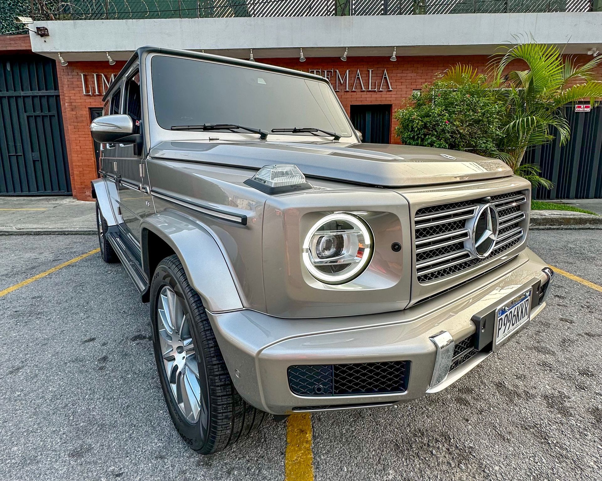 Un SUV Mercedes-Benz Clase G de color beige estacionado frente a un edificio.