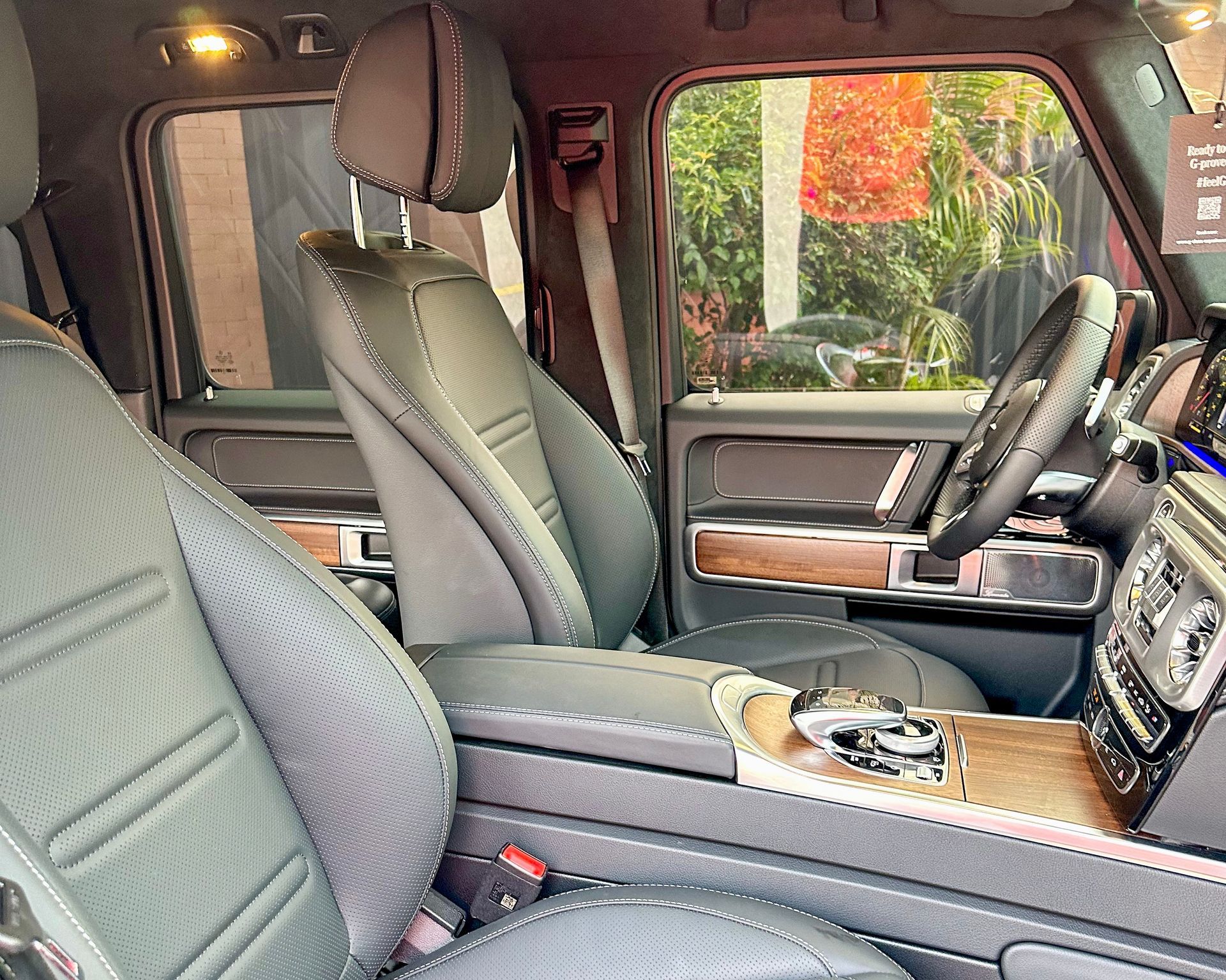 Interior de un SUV de lujo con asientos de cuero gris, detalles en madera y un volante visible 