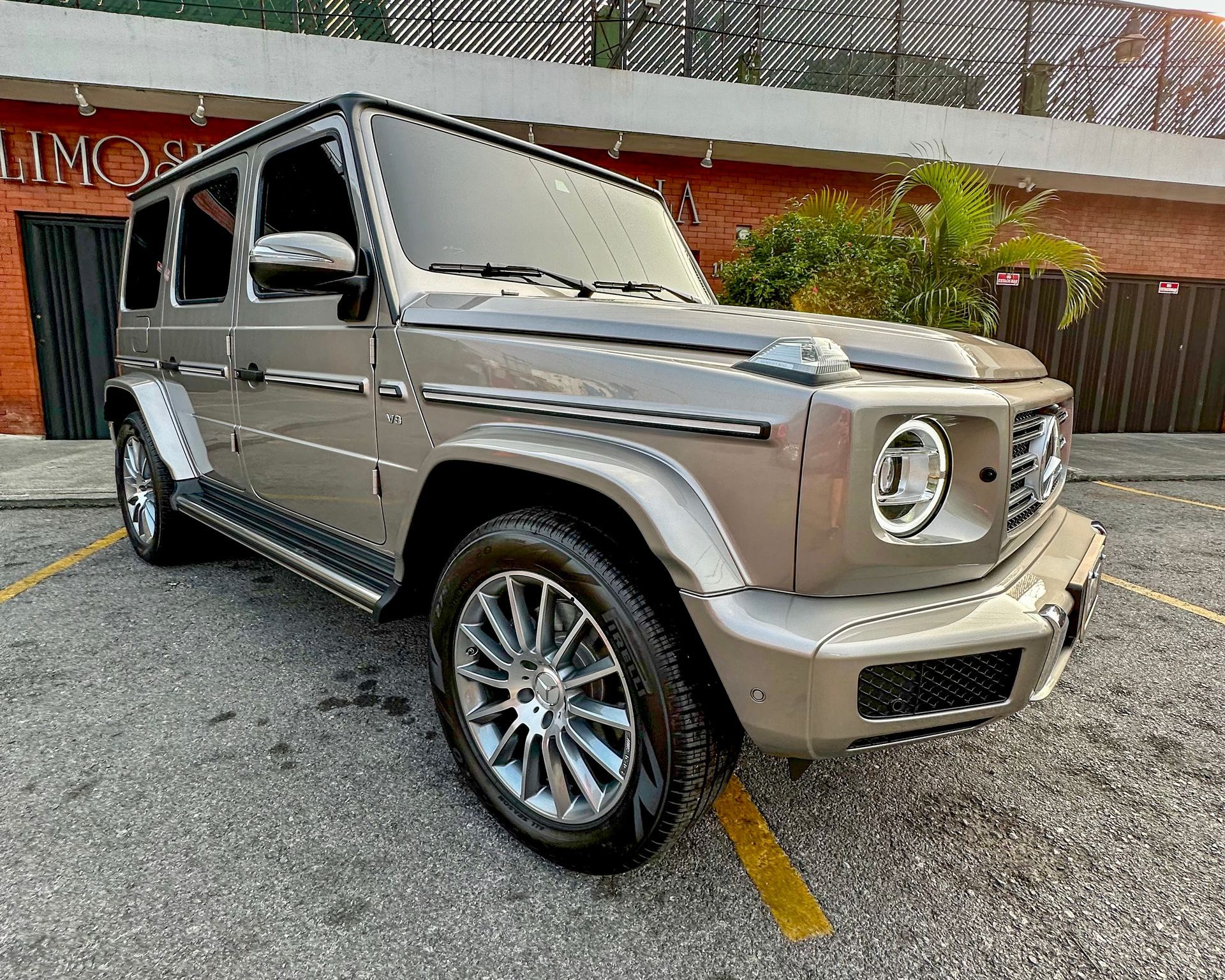 SUV Mercedes G-Wagon plateado estacionado en ángulo en una calle, con detalles cromados y ruedas grandes.