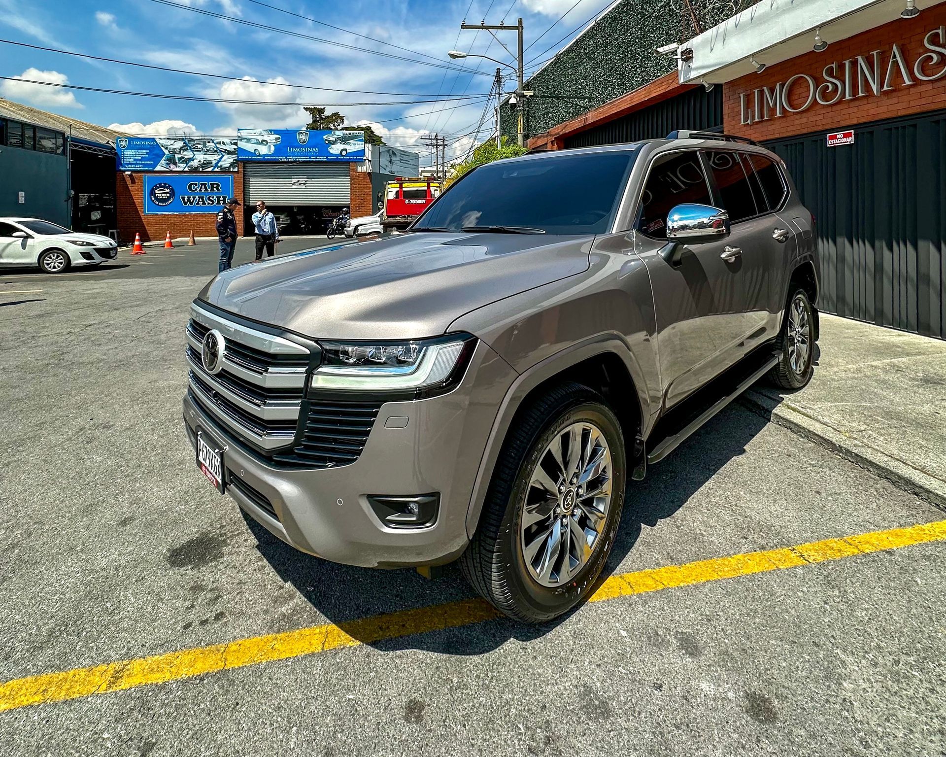 Un SUV GMC plateado estacionado en ángulo en un lote junto a un edificio rojo.