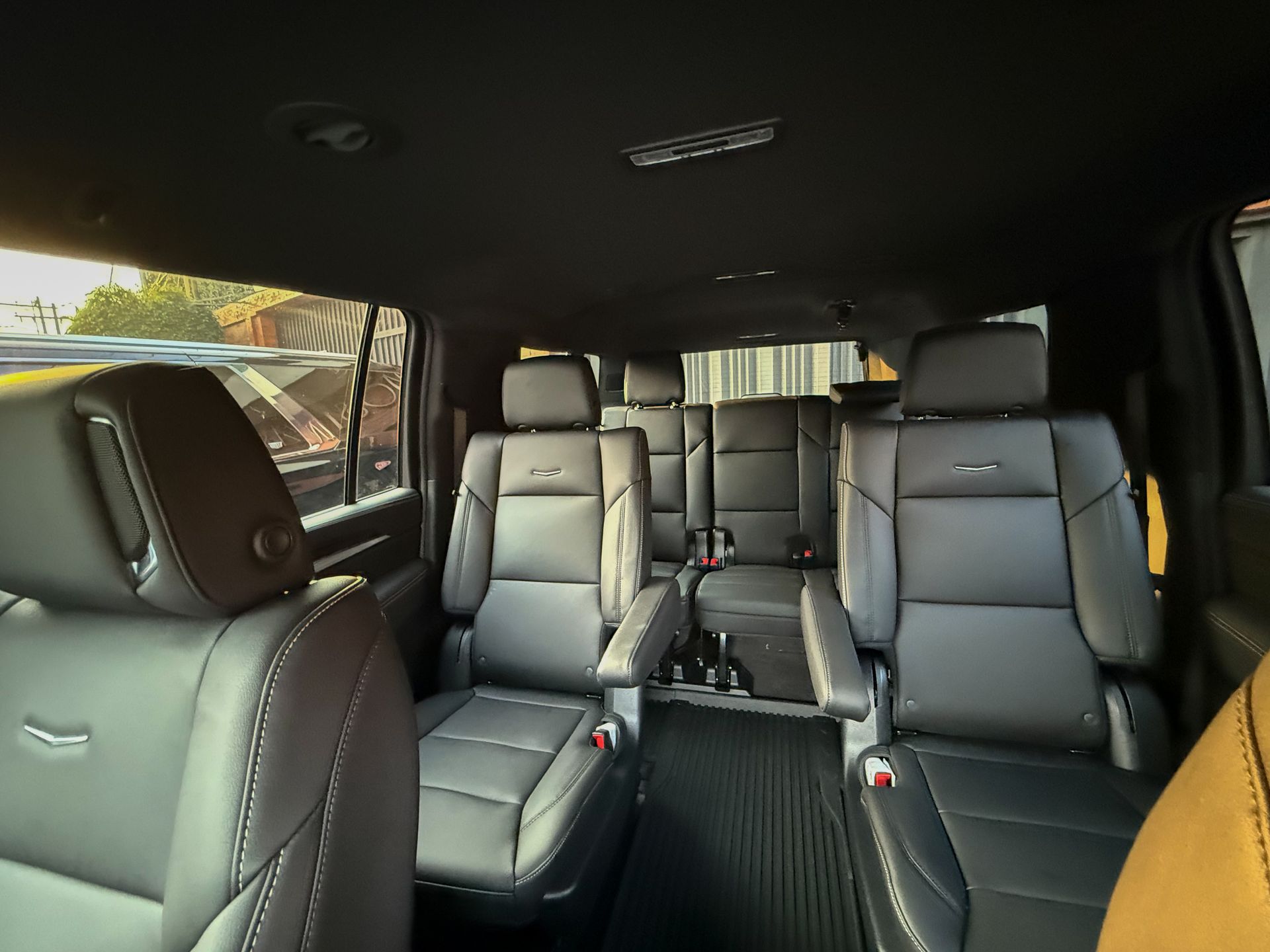 Interior de un SUV de lujo con asientos de cuero negro y un asiento delantero amarillo visible