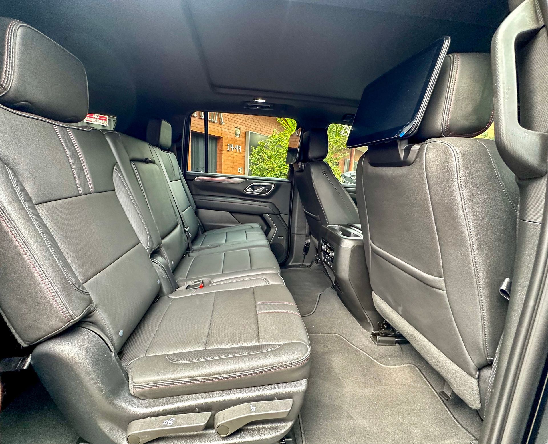 Interior de SUV en cuero negro con asientos traseros abatidos y vista a través de la puerta lateral abierta.