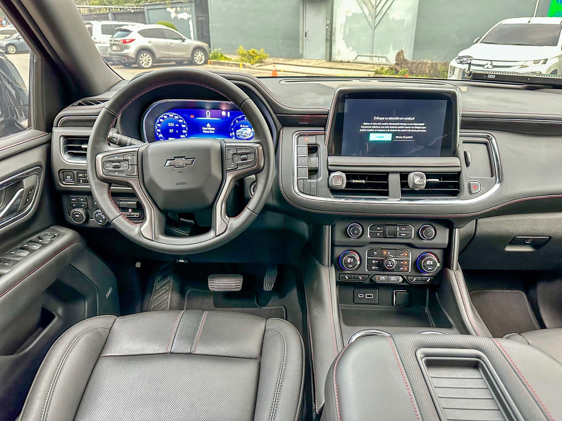 Interior de la camioneta con asientos de cuero negro, volante, tablero digital y pantalla táctil central.