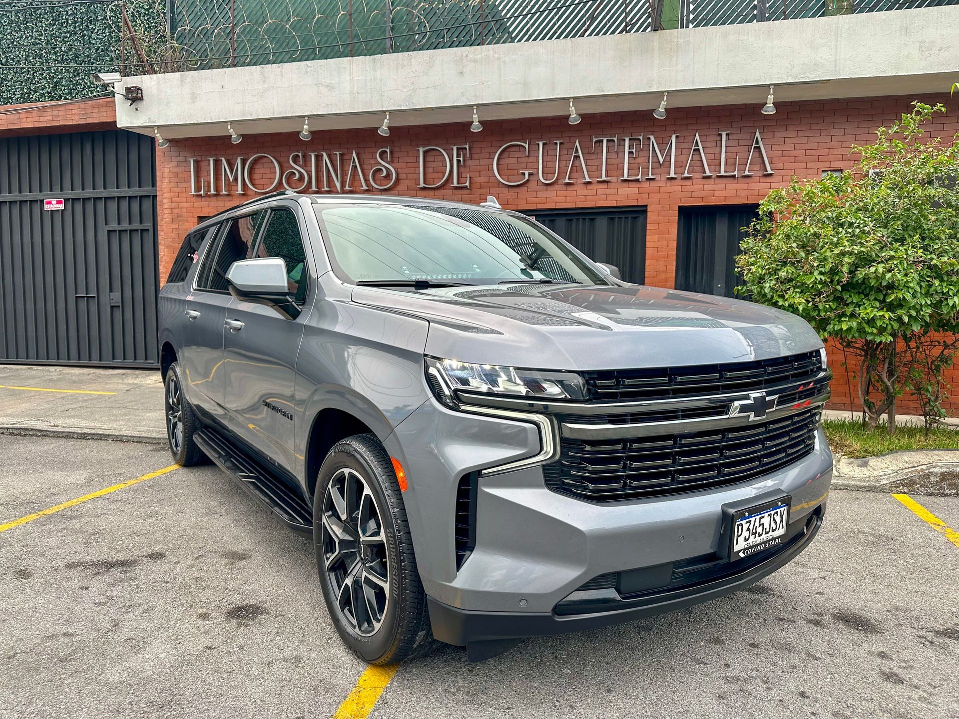 SUV plateado estacionado afuera de un edificio con la inscripción “Limosinas de Guatemala”.