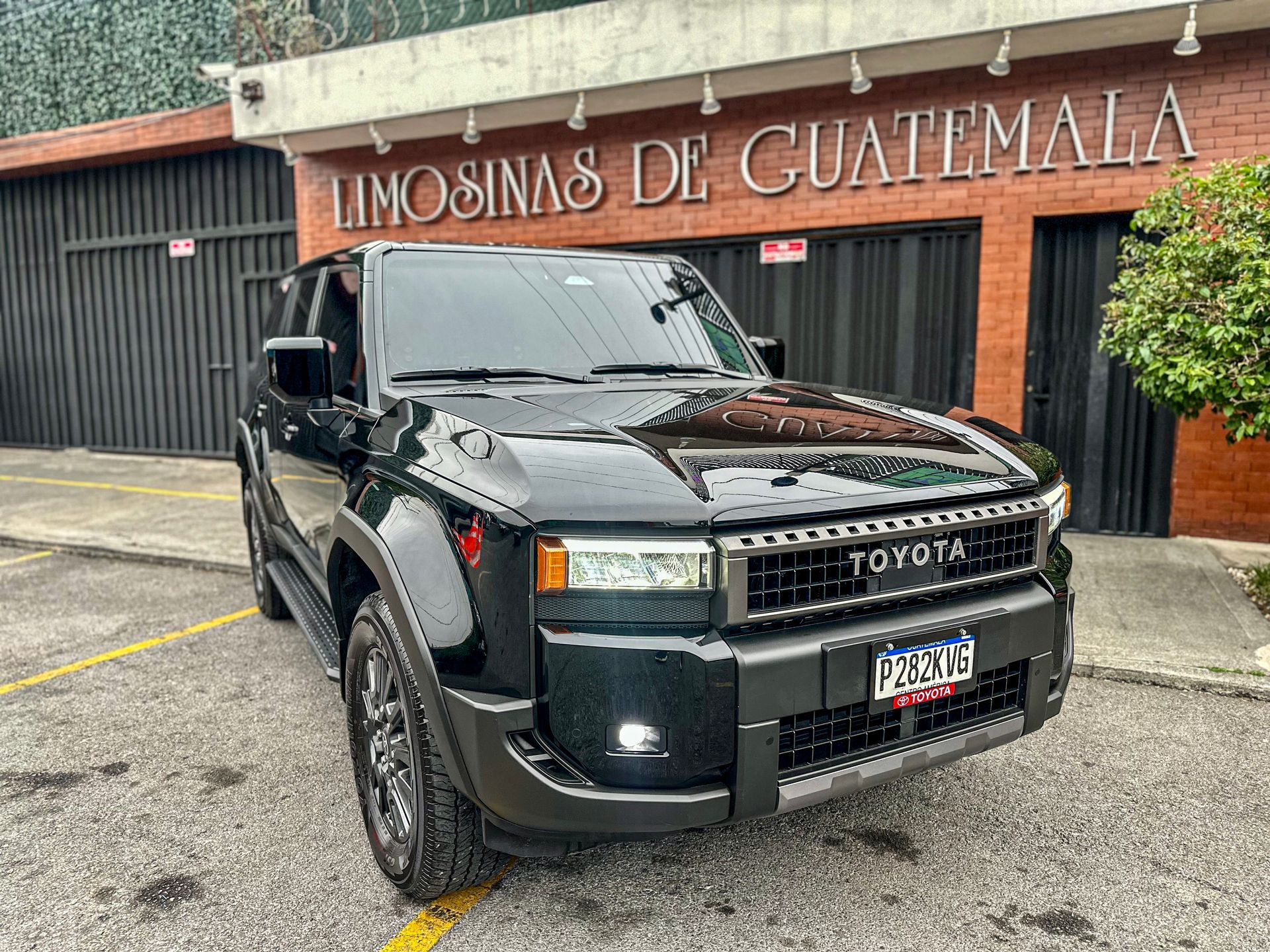 Camioneta Toyota negra estacionada afuera de un edificio con la inscripción “Limusina de Guatemala”.