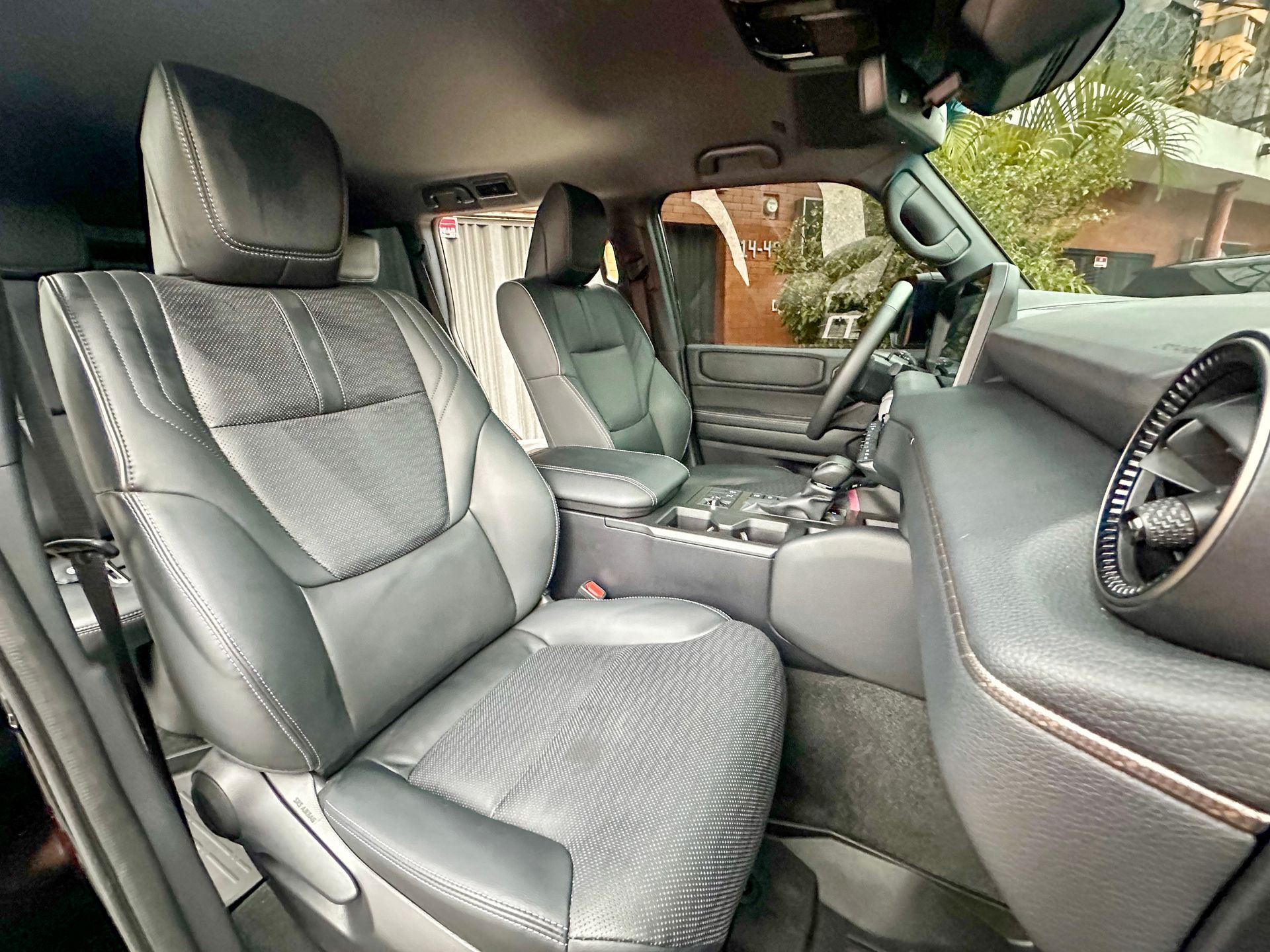 Interior de automóvil de cuero negro con el asiento del pasajero delantero, el tablero y la consola central a la vista.