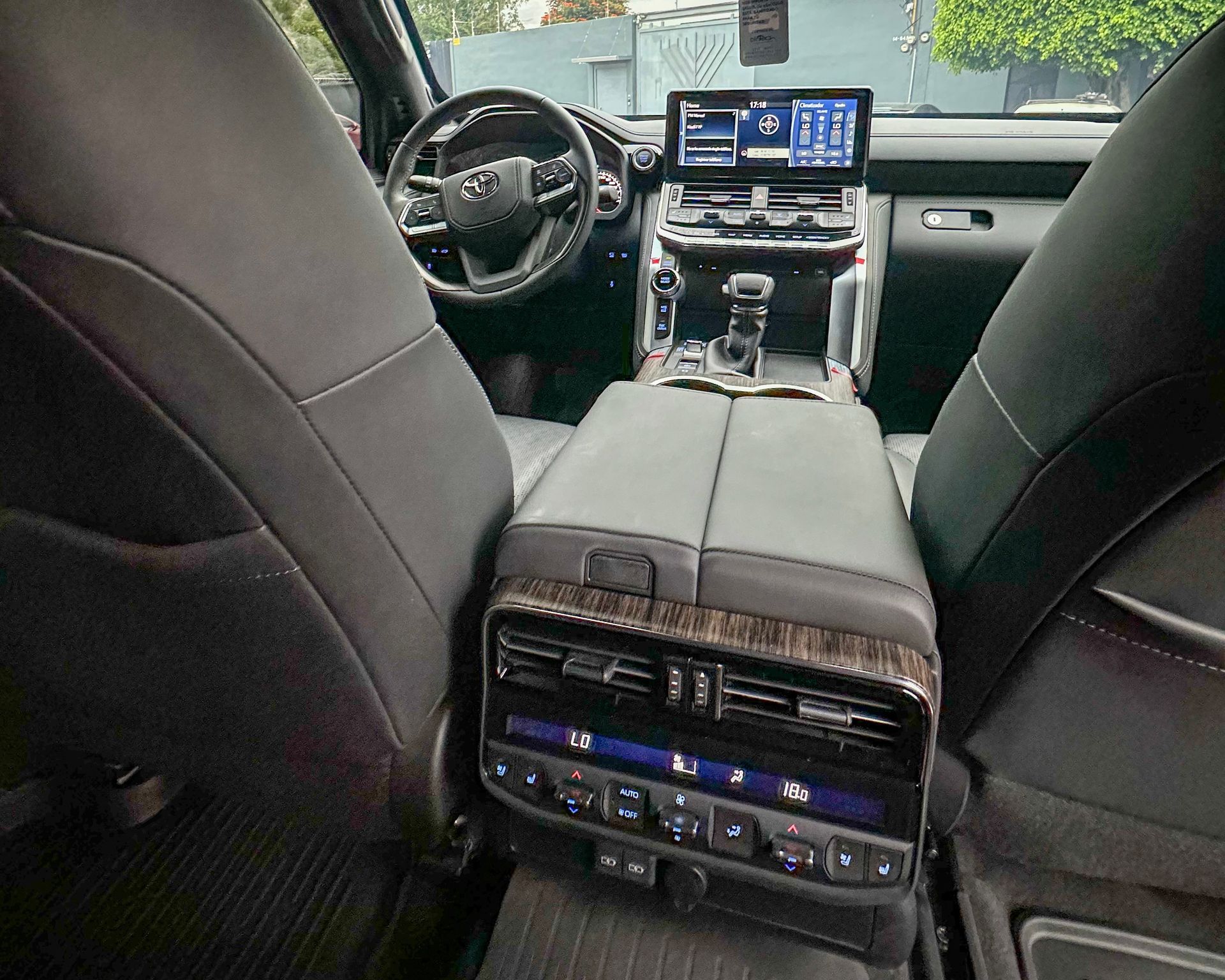 Vista del interior del coche desde el asiento trasero, mostrando los asientos de cuero negro, la consola central