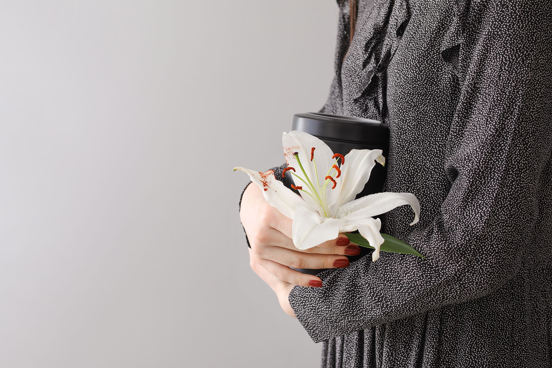 a woman is holding a white lily in her hands .