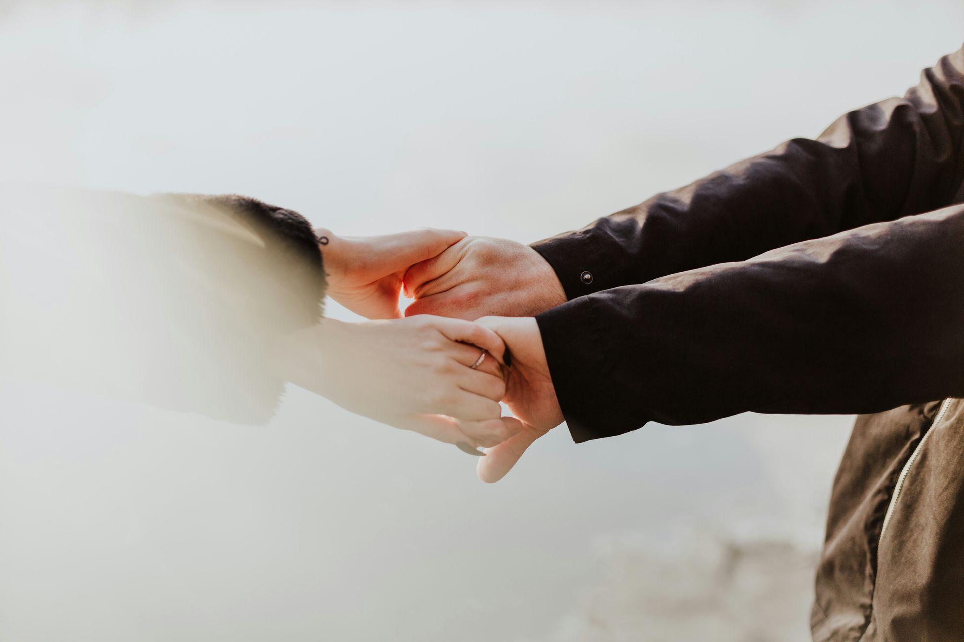 a man and a woman are holding hands in front of a body of water .