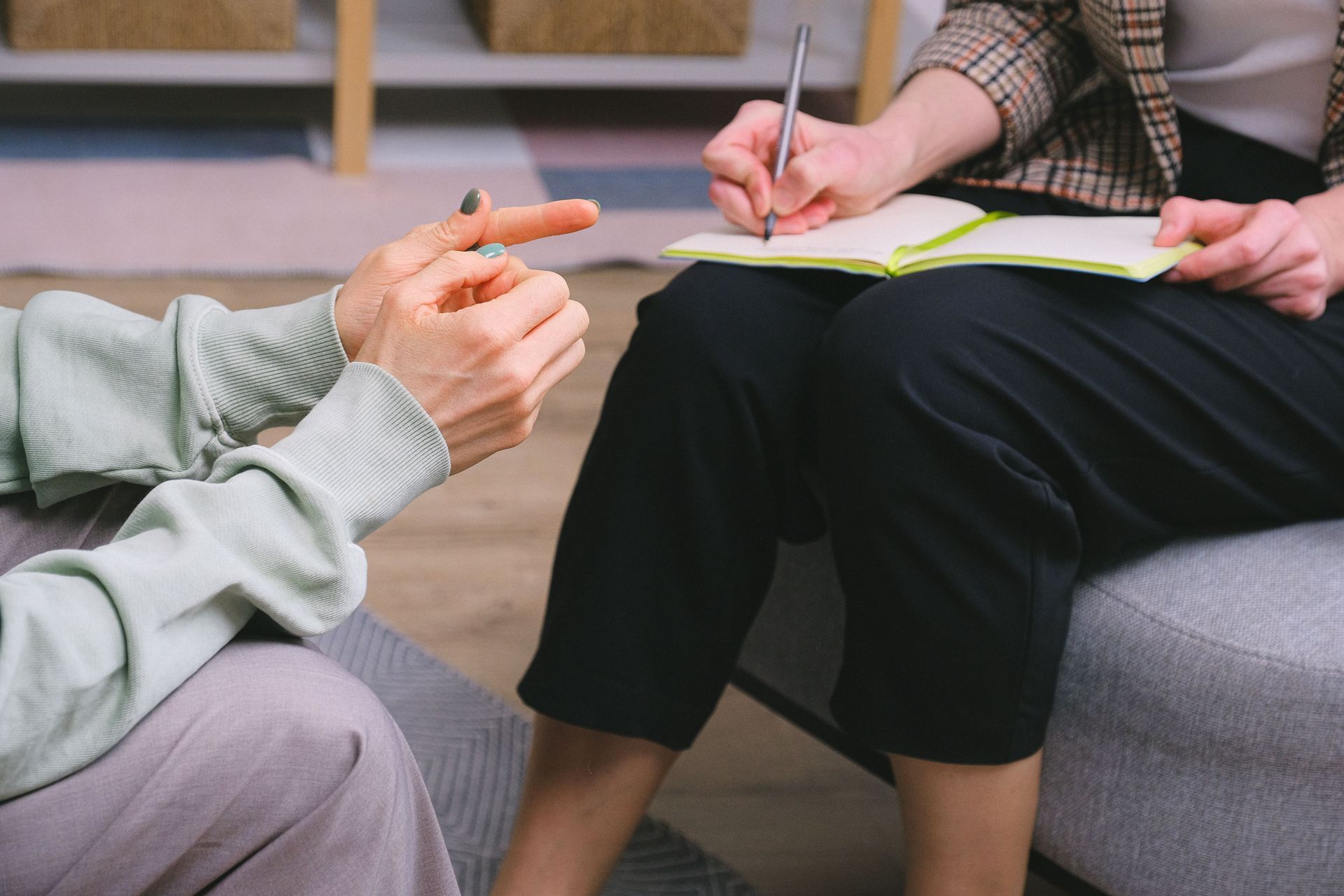 Two people seated in conversation, one taking notes on a clipboard