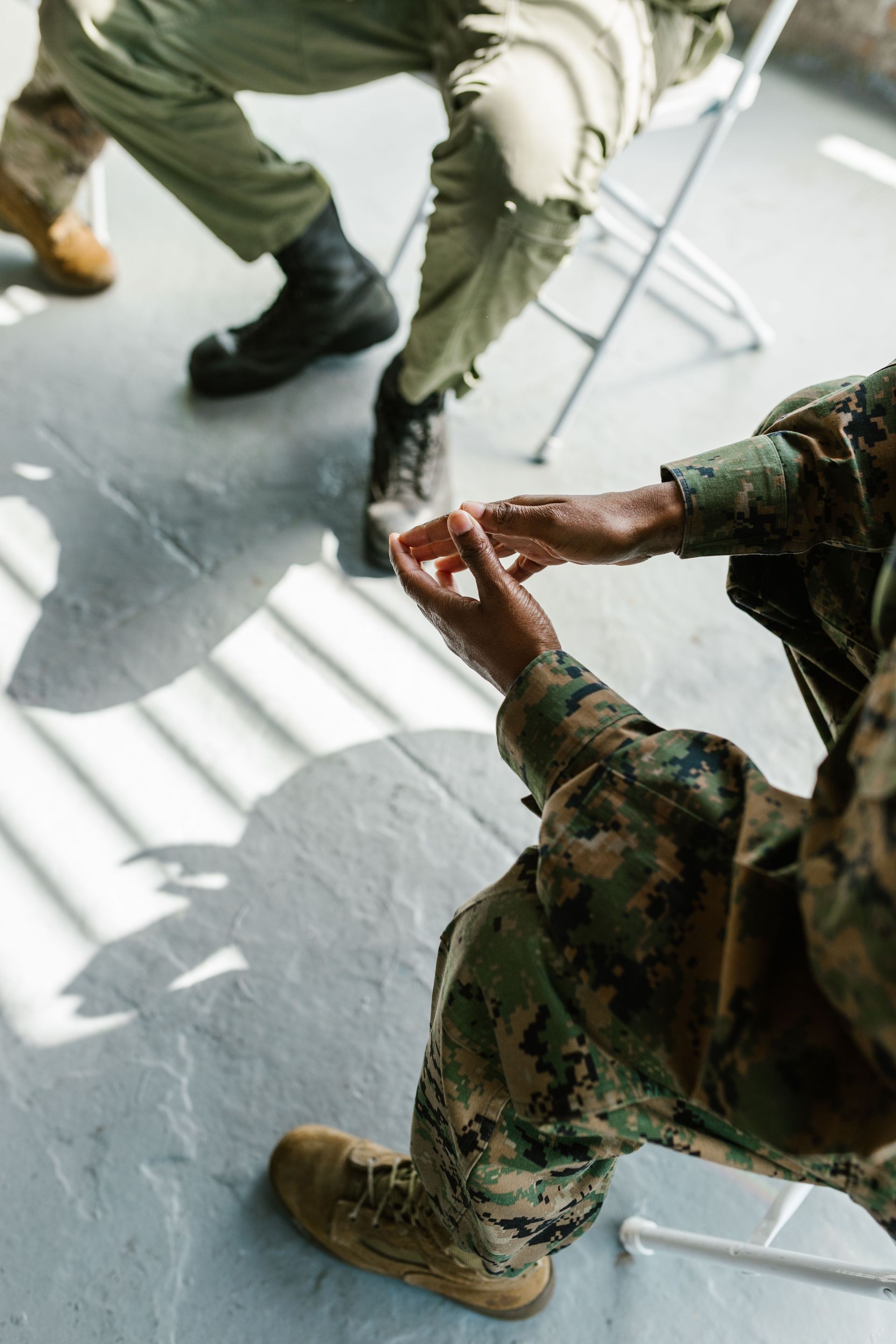 People talking about their PTSD, seated on chairs, one holding a small object in a bright room